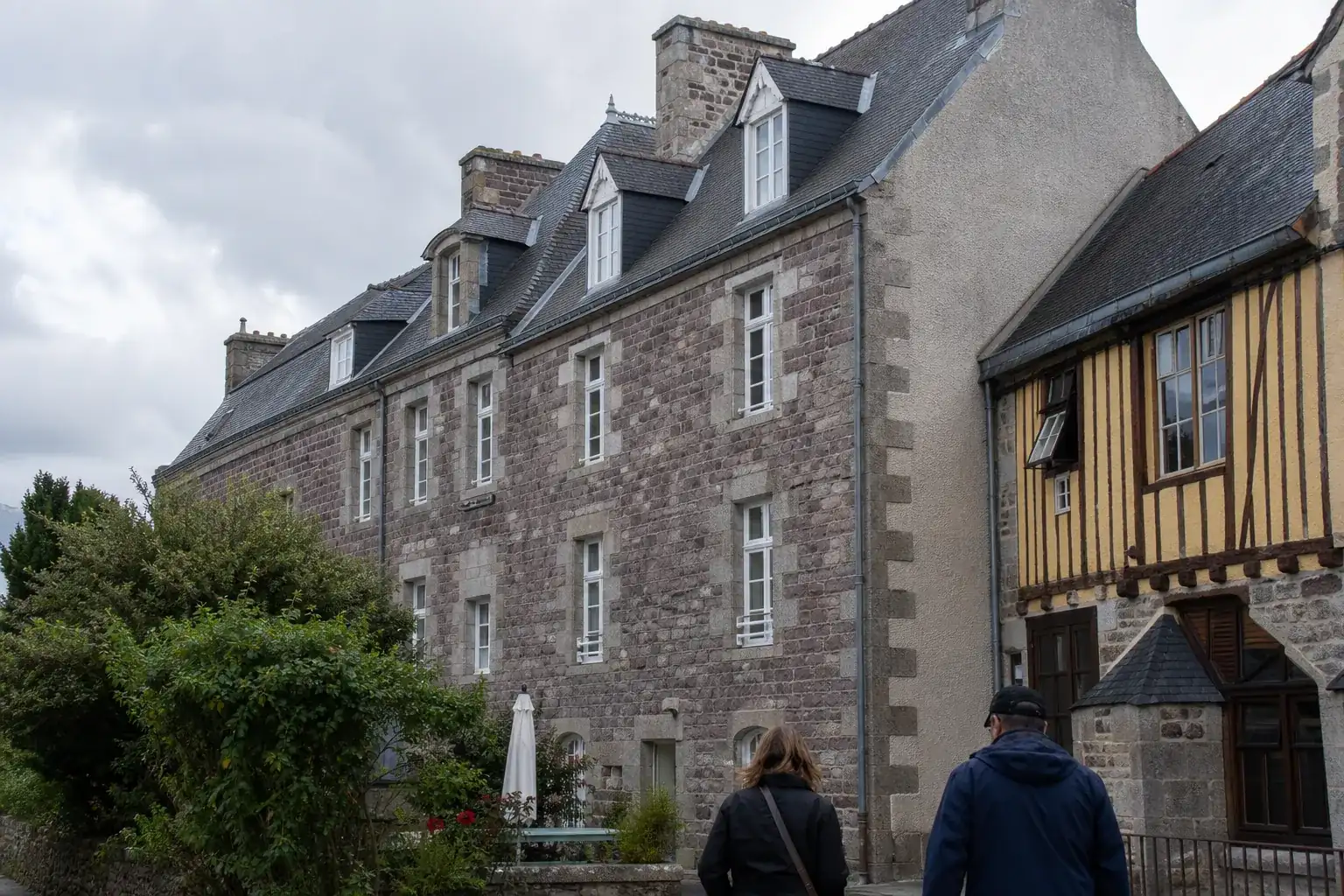 Immeuble de quatre étages en granit et pierre claire, toit d’ardoise à forte pente percé de lucarnes, faîtage en zinc