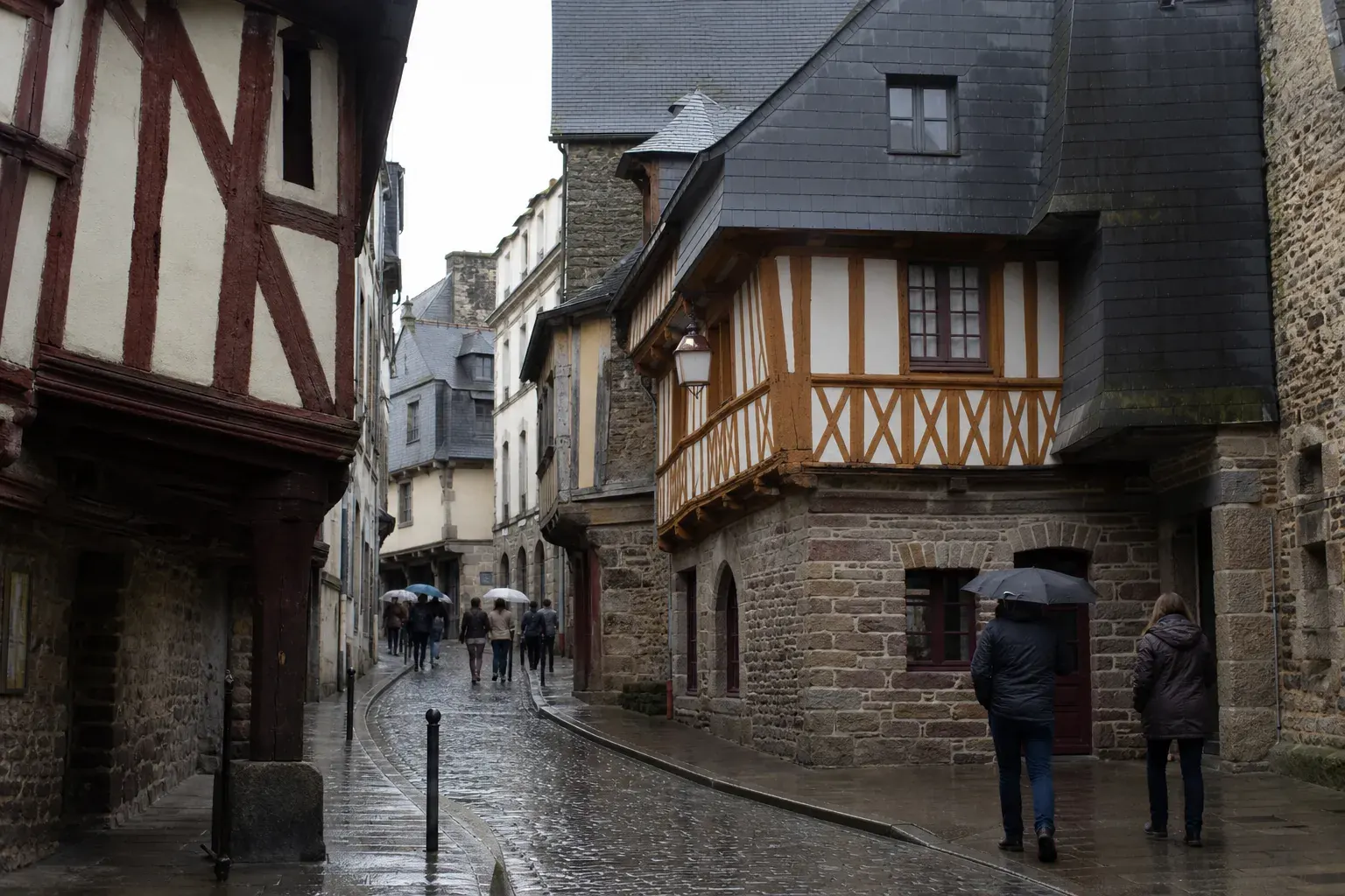 Rue de maisons à pans de bois d’un centre ancien breton, encorbellements et panneaux peints sous des toits d’ardoise à forte pente